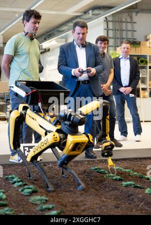 9 luglio 2024, Baden-Württemberg, Tübingen: Il ministro federale del lavoro Hubertus Heil (SPD) e Wieland Brendl (l) del Max Planck Institute for Intelligent Systems partecipano a una dimostrazione di un robot agricolo. Heil visitò l'istituto come parte del suo viaggio estivo. Foto: Marijan Murat/dpa Foto Stock