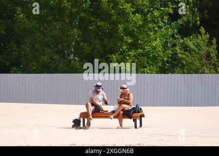 Una coppia di anziani siede su una panchina su una delle spiagge del Golfo di Finlandia in una calda giornata estiva a Sestroretsk, fuori San Pietroburgo. Foto Stock