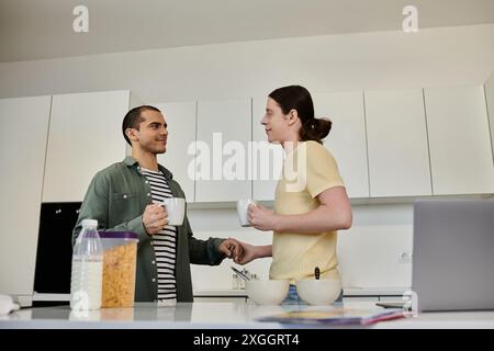 Una giovane coppia gay gode di una mattinata informale insieme nel loro moderno appartamento, sorseggiando un caffè e chiacchierando. Foto Stock