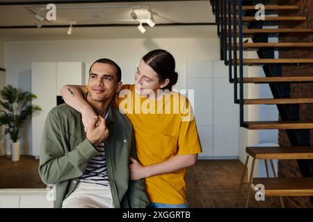 Una giovane coppia gay in un abbigliamento informale gode di tempo di qualità in un appartamento moderno con una scala di legno. Foto Stock