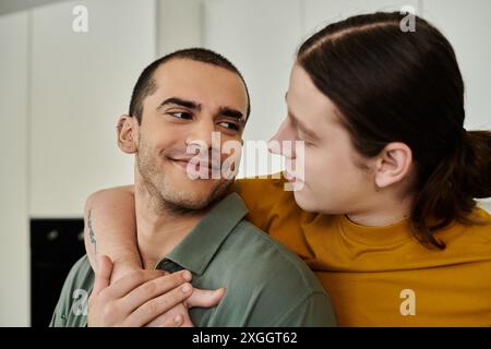 Una giovane coppia gay gode di un momento tenero insieme nel loro appartamento moderno. Foto Stock