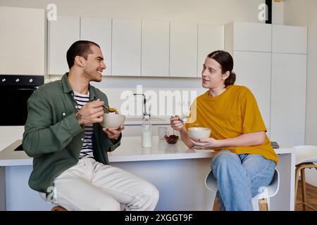 Una giovane coppia gay gode di una colazione rilassata insieme nel loro moderno appartamento. Foto Stock