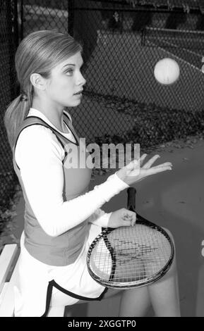 Adolescente caucasica che lancia una palla da tennis in aria tenendo una racchetta. Foto Stock