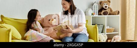 Una madre bruna e sua figlia con una gamba protesica trascorrono del tempo prezioso leggendo un libro insieme su un divano giallo. Foto Stock