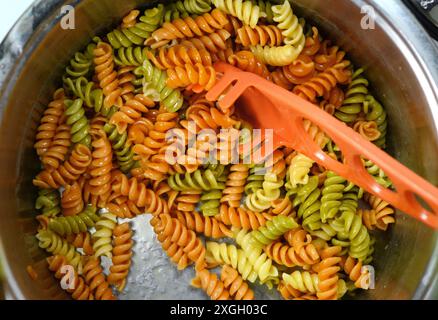 Pasta rotini in tre colori. Pasta fusilli fondo tricolore. Consistenza astratta di pasta colorata. Schema dei maccheroni. Cibo multicolore brillante. Foto Stock