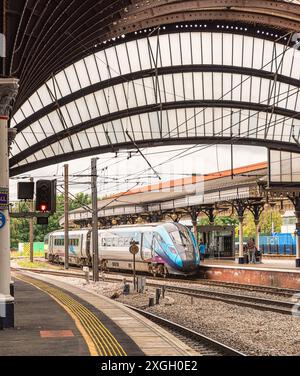 Lo storico arco curvo copre una piattaforma della stazione ferroviaria e un treno aspetta di partire. I passeggeri sono sulla piattaforma. Foto Stock