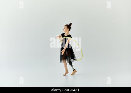 Una giovane ragazza con una gamba protesica esegue una routine di ginnastica con un cerchio. Foto Stock