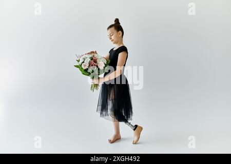 Una giovane ginnasta con una gamba protesica posa graziosamente tenendo un bouquet di fiori. Foto Stock