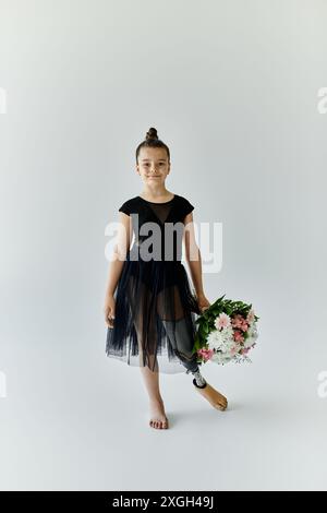 Una giovane ragazza con una gamba protesica posa con dei fiori mentre indossa un filetto nero e un tutù. Foto Stock