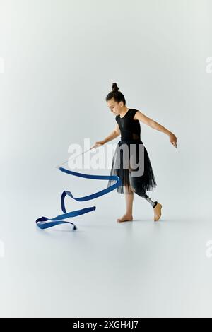 Una giovane ragazza con una gamba protesica esegue ginnastica con un nastro blu. Foto Stock