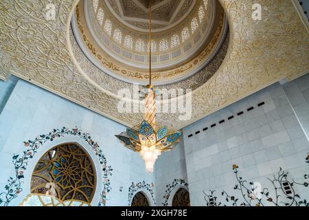 Abu Dhabi, Emirati Arabi Uniti - 4 gennaio 2024: Interni maestosi della moschea con lampadario decorato Foto Stock