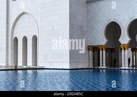 Abu Dhabi, Emirati Arabi Uniti - 4 gennaio 2024: Eleganti archi e acque riflettenti presso la grande Moschea dello sceicco Zayed di Abu Dhabi. Foto Stock