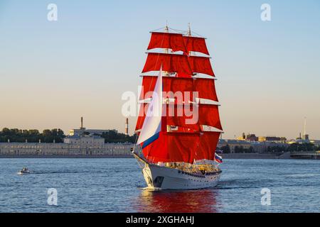 SAN PIETROBURGO, RUSSIA - 27 GIUGNO 2024: Una nave con vele scarlatte (Brig 'Russia') nelle acque della Neva in una serata di sole. Prove per l'AN Foto Stock