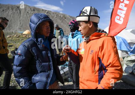 (240709) -- AKTO, 9 luglio 2024 (Xinhua) -- mentre la squadra di alpinismo sta per partire, li Yuan (L), il capo della spedizione Muztagh Ata dell'Associazione Alpinista dello Xinjiang, dà istruzioni a Taxibayi Janibaiki riguardo al posizionamento delle merci trasportate nel campeggio e altre questioni di sicurezza nella regione autonoma di Xinjiang Uygur della Cina nord-occidentale, 4 luglio 2024. Il Muztagh Ata, situato sull'altopiano di Pamir a un'altitudine di oltre 7.500 metri nella regione autonoma di Xinjiang Uygur, nella Cina nord-occidentale, è un'attrazione per gli appassionati di alpinismo provenienti da tutto il mondo. Durante il clim Foto Stock