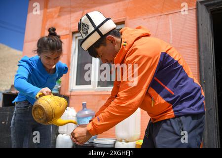 (240709) -- AKTO, 9 luglio 2024 (Xinhua) -- dopo essere sceso dalla montagna, Taxibayi Janibaiki è assistito dalla sorella minore (L) mentre si lava le mani ad Akto, nella regione autonoma di Xinjiang Uygur, nel nord-ovest della Cina, 5 luglio 2024. Il Muztagh Ata, situato sull'altopiano di Pamir a un'altitudine di oltre 7.500 metri nella regione autonoma di Xinjiang Uygur, nella Cina nord-occidentale, è un'attrazione per gli appassionati di alpinismo provenienti da tutto il mondo. Durante la stagione delle arrampicate, la gente si riunisce nel villaggio di Subax, nella contea di Akto, ai piedi del Muztagh Ata per l'alpinismo. Per quanto riguarda le persone locali che sono fa Foto Stock