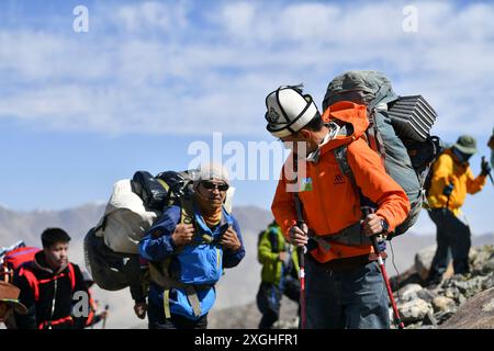 (240709) -- AKTO, 9 luglio 2024 (Xinhua) -- salendo la montagna, Taxibayi Janibaiki (fronte) si gira per osservare i suoi compagni dietro di lui nella regione autonoma Xinjiang Uygur del nord-ovest della Cina, 4 luglio 2024. Il Muztagh Ata, situato sull'altopiano di Pamir a un'altitudine di oltre 7.500 metri nella regione autonoma di Xinjiang Uygur, nella Cina nord-occidentale, è un'attrazione per gli appassionati di alpinismo provenienti da tutto il mondo. Durante la stagione delle arrampicate, la gente si riunisce nel villaggio di Subax, nella contea di Akto, ai piedi del Muztagh Ata per l'alpinismo. Per quanto riguarda la gente del posto che ha familiarità con il Foto Stock