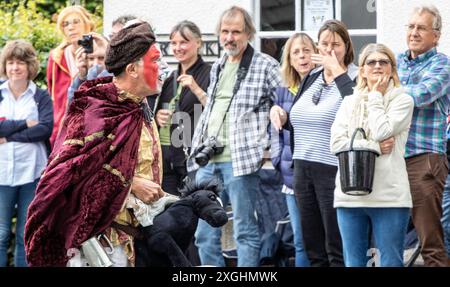 I Rendham Mummers celebrano il solstizio d'estate con la tradizionale vernice per il viso, 2018 e la strada fuori dal pub White Horse con traffico di passaggio. Foto Stock