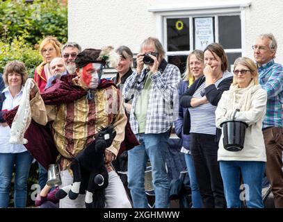 I Rendham Mummers celebrano il solstizio d'estate con la tradizionale vernice per il viso, 2018 e la strada fuori dal pub White Horse con traffico di passaggio. Foto Stock