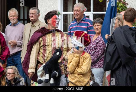 I Rendham Mummers celebrano il solstizio d'estate con la tradizionale vernice per il viso, 2018 e la strada fuori dal pub White Horse con traffico di passaggio. Foto Stock