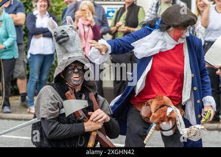 I Rendham Mummers celebrano il solstizio d'estate con la tradizionale vernice per il viso, 2018 e la strada fuori dal pub White Horse con traffico di passaggio. Foto Stock