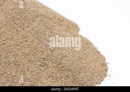 Condimento piccante con pepe nero macinato versato su sfondo bianco. Foto Stock