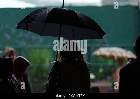 9 luglio 2024; All England Lawn Tennis and Croquet Club, Londra, Inghilterra; Wimbledon Tennis Tournament, 9° giorno; gli spettatori di Wimbledon cercano di mantenersi asciutti sotto la forte pioggia Foto Stock