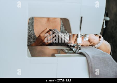 Primo piano di una giovane sarta che siede ad una macchina da cucire Foto Stock