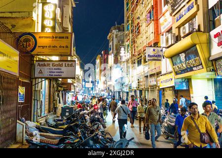 Ahmenabad, India - 13 ottobre 2023: Le persone si vedono camminare di notte nel centro della città tra gioiellerie e negozi d'oro. Affollata e trafficata strada indiana Foto Stock