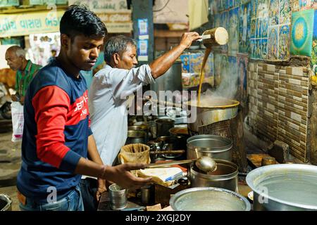 Ahmenabad, India - 20 ottobre 2023: Un venditore di chai di strada viene visto vendere chai di notte. Vecchio indiano che fa un lavoro informale, concetto di sostentamento in Foto Stock