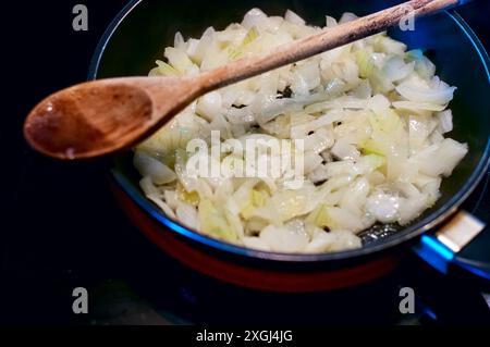 Sizzle dorato. Saltando le cipolle tritate in una padella Foto Stock