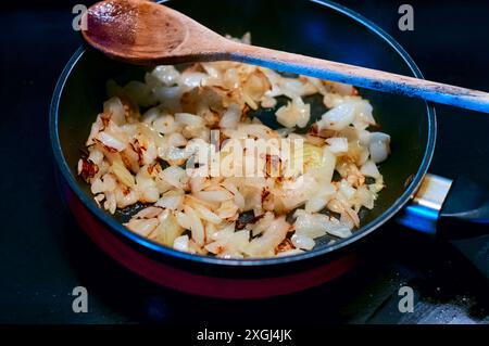 Sizzle dorato. Saltando le cipolle tritate in una padella Foto Stock