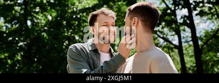 Una coppia gay con la barba gode di una giornata di sole nel parco, condividendo un tenero momento di affetto. Foto Stock