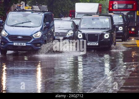 Londra, Regno Unito. 9 luglio 2024. Le auto si tuffano in una grande pozzanghera su Euston Road mentre la forte pioggia bagna la capitale. Crediti: Vuk Valcic/Alamy Live News Foto Stock