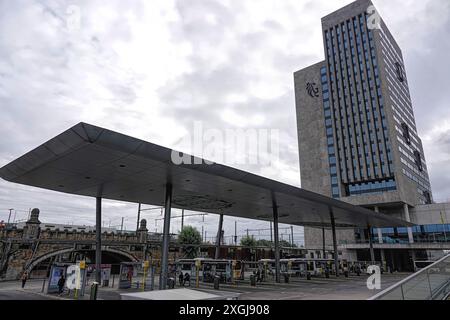 Moderna stazione degli autobus con un alto edificio per uffici e cielo nuvoloso sullo sfondo a Gand, Belgio Foto Stock