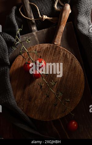 Un tagliere di legno con un po' di pomodoro ciliegino sul suo ramo. Ci sono dei pomodori mancanti sulla vite Foto Stock