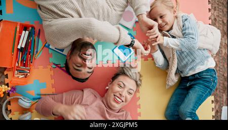 In alto, la famiglia e felice sul pavimento con giochi per divertimento, divertimento e Unione. Persone, genitori e ragazza o ragazzo con il sorriso nel giocare a puzzle a casa Foto Stock