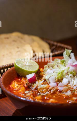 Delizioso piatto di tradizionale pozolo rosso messicano con ravanello, lattuga, ominide, maiale e peperoncino secco. Accompagnato da caffè, salsa rossa messicana, tosta Foto Stock