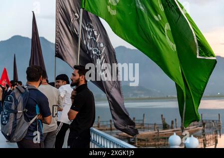 I musulmani sciiti del Kashmir si vedono tenere bandiere religiose su una strada durante Muharram. Muharram iniziò in Kashmir con profonda riverenza, specialmente tra la comunità musulmana sciita, commemorando il martirio dell'imam Hussain nella battaglia di Karbala. I primi dieci giorni, che culminano con l'Ashura, presentano processioni solenni in cui i lori vestiti di nero portano striscioni e eseguono ritmici battendo il petto. Si tengono raduni Majlis dove gli studiosi religiosi raccontano gli eventi di Karbala, e le recitazioni emotive di Marsiya sono comuni. Intricati standard Taziyah e Alam, simboleggiano l'islamico Foto Stock