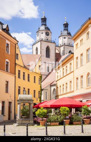 L'area del "mercato del legno" (Holzmarkt) della città di Wittenberg (Lutherstadt) in Sassonia-Anhalt, in Germania con la chiesa di Santa Maria sullo sfondo e una frère Foto Stock