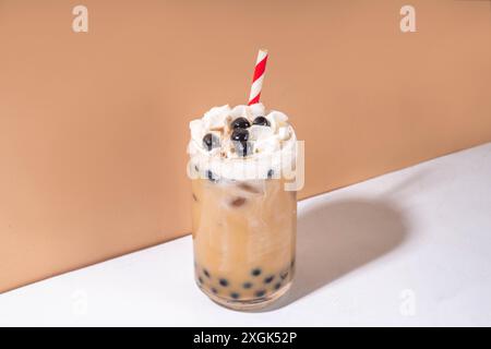 Classico boba bobble tea con perle di tapioca e crema non casearia montata sopra il bicchiere, dolce dolce dolce estivo su sfondo bianco della tavola c Foto Stock