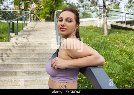 Una donna sportiva stanca e di grandi dimensioni che riposa sulle scale Foto Stock