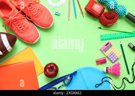 Telaio realizzato con attrezzature sportive, mele e cancelleria diversa su sfondo verde Foto Stock