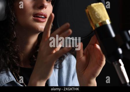 Donna che canta nel microfono in uno studio di registrazione professionale, primo piano Foto Stock
