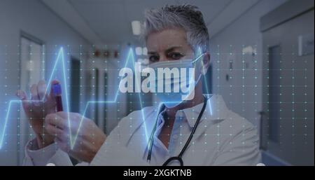Immagine del montiore della frequenza cardiaca contro il medico donna caucasico che tiene una bottiglia di fiala in ospedale Foto Stock