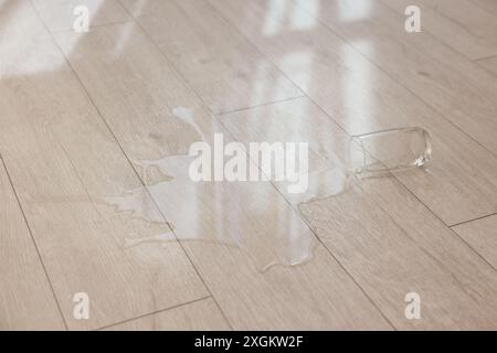 Bicchiere con bibita versata su pavimento in legno Foto Stock