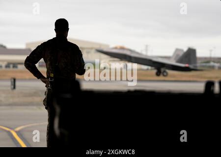 Andrea Colotti, un ufficiale degli affari pubblici dello European Air Transport Command, guarda come un F-22 Raptor assegnato al 3rd Wing della U.S. Air Force decolla durante l'esercitazione Arctic Defender 24 presso Joint base Elmendorf-Richardson, Alaska, 8 luglio 2024. Arctic Defender è un'esercitazione guidata dall'aeronautica militare tedesca che offre un'opportunità unica per integrare varie forze in un addestramento congiunto, di coalizione e multilaterale da basi operative avanzate simulate e fa parte di diversi esercizi nell'ambito di Pacific Skies 24. Arctic Defender è un'esercitazione condotta dall'aeronautica militare tedesca che offre un'opportunità unica Foto Stock