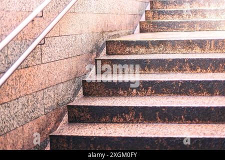 Scala con ringhiera e ombra sui gradini. I gradini sono realizzati in pietra e sembrano usurati Foto Stock