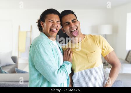 Diverse coppie gay godono di un momento divertente a casa. Le loro risate aggiungono un'atmosfera calda e invitante all'accogliente spazio abitativo. Foto Stock