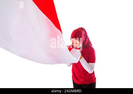 Ritratto di una donna che baciava la bandiera indonesiana come simbolo di orgoglio nel giorno dell'indipendenza indonesiana isolato su uno sfondo bianco Foto Stock