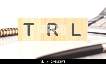 Livello di disponibilità della tecnologia TRL. Parole TRL su cubi di legno in una composizione con una calcolatrice, una penna e un frammento di un taccuino Foto Stock